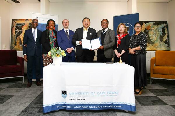 Michael Addo, Erika George, Paul Miller, Marcus Cole, Danwood Chirwa, Christine Venter, and Fatima Khan standing with the MOU