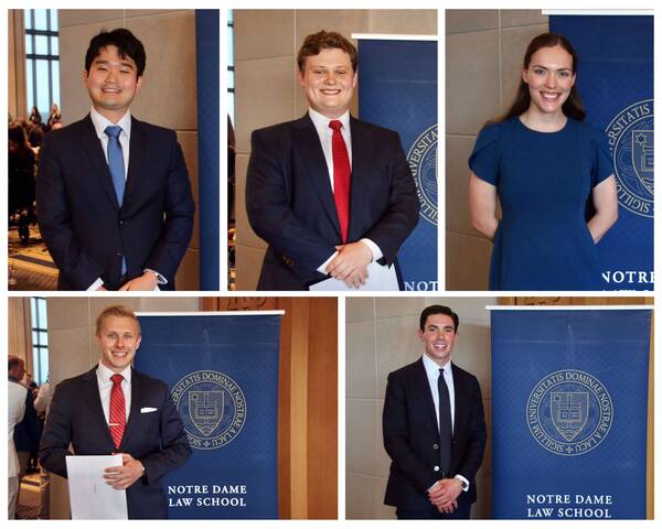 Five smiling individuals in formal attire, with Notre Dame Law School banners.
