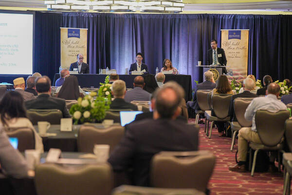 Panelists speak at Notre Dame Law School Religion & Liberty Summit under "We Hold These Truths" banners to an audience.