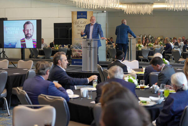 A man in a blue plaid blazer speaks from a podium at the Notre Dame Law Religious Liberty Summit to a seated audience.