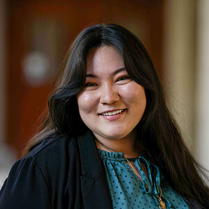 Young woman with dark hair smiles, wearing a teal polka-dot blouse and black jacket. (Maria Valera)